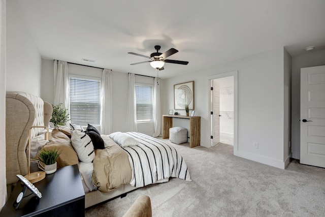 carpeted bedroom featuring a walk in closet and ceiling fan