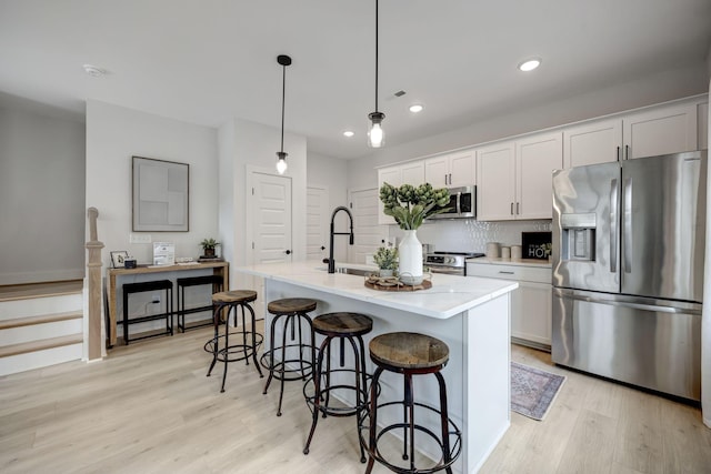 kitchen featuring a kitchen island with sink, sink, white cabinetry, and appliances with stainless steel finishes