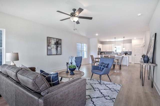 living room with light hardwood / wood-style flooring and ceiling fan