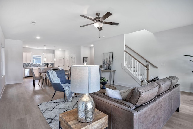 living room featuring ceiling fan, sink, and light hardwood / wood-style flooring