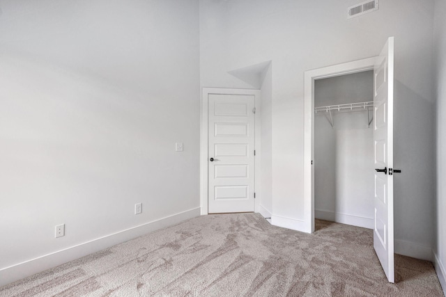 unfurnished bedroom with light carpet and a closet