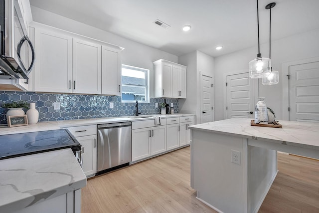 kitchen featuring sink, appliances with stainless steel finishes, white cabinetry, hanging light fixtures, and a kitchen island