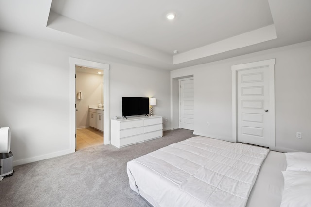 carpeted bedroom featuring a tray ceiling, ensuite bath, and a closet