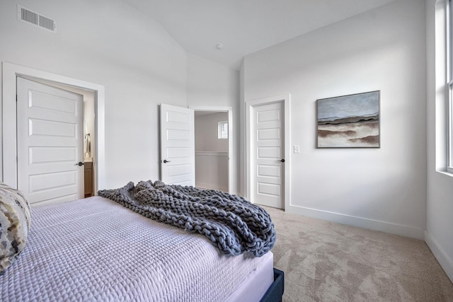 bedroom with multiple windows, lofted ceiling, and light colored carpet