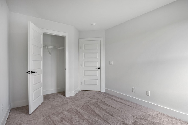 unfurnished bedroom with light colored carpet and a closet