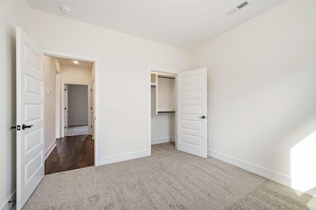 unfurnished bedroom with a closet and dark colored carpet