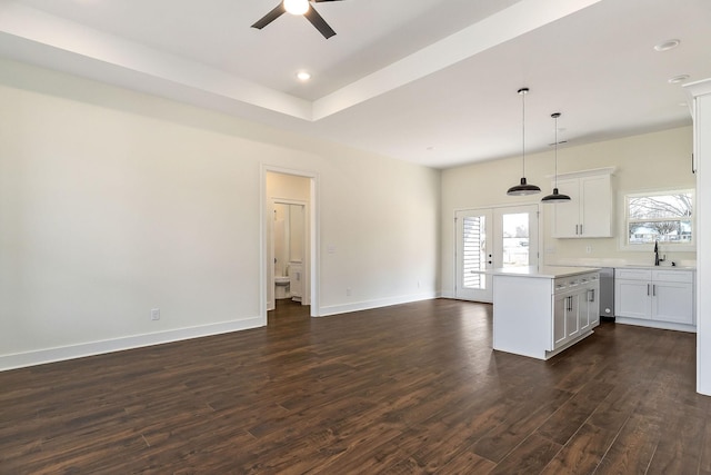 kitchen with white cabinetry, a center island, dark hardwood / wood-style flooring, sink, and pendant lighting