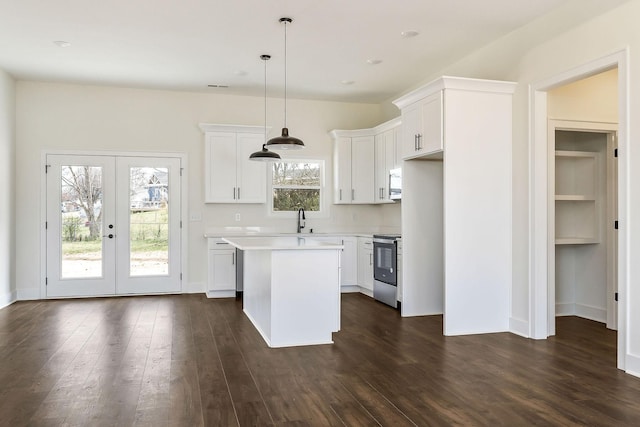 kitchen featuring stainless steel electric range oven, a center island, white cabinets, hanging light fixtures, and french doors