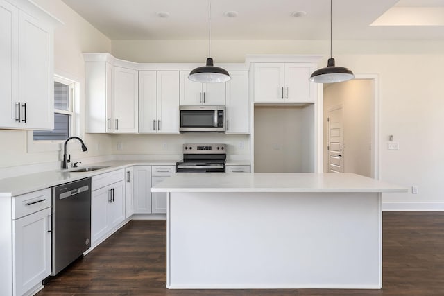 kitchen with sink, appliances with stainless steel finishes, a kitchen island, and hanging light fixtures