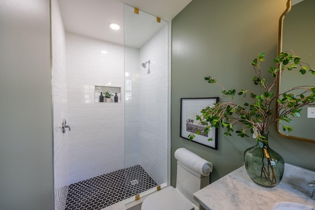 bathroom with vanity, tiled shower, and toilet