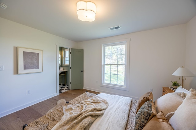 bedroom with ensuite bath and wood-type flooring