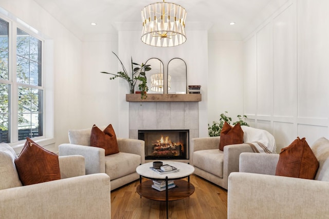 living room with ornamental molding, a fireplace, a chandelier, and light hardwood / wood-style flooring