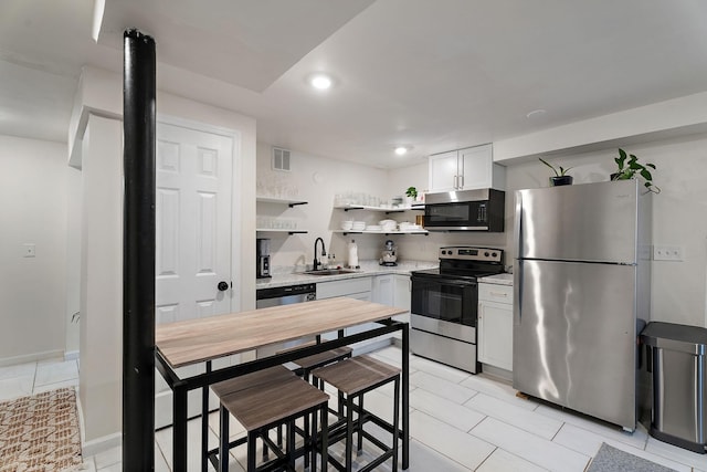 kitchen with white cabinetry, appliances with stainless steel finishes, light tile patterned flooring, and sink