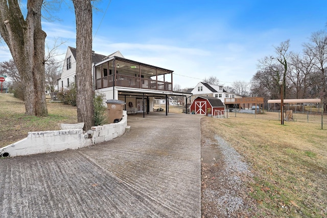 view of front of home with a sunroom, a front yard, and a storage shed