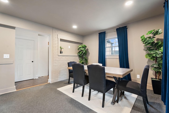 dining room featuring dark carpet and brick wall