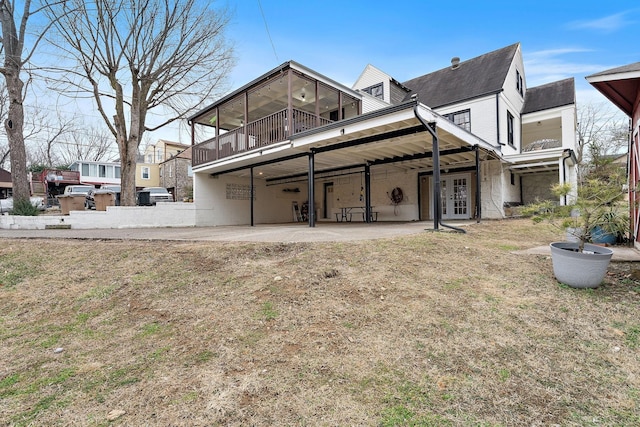 back of house featuring a sunroom, a patio area, and a lawn