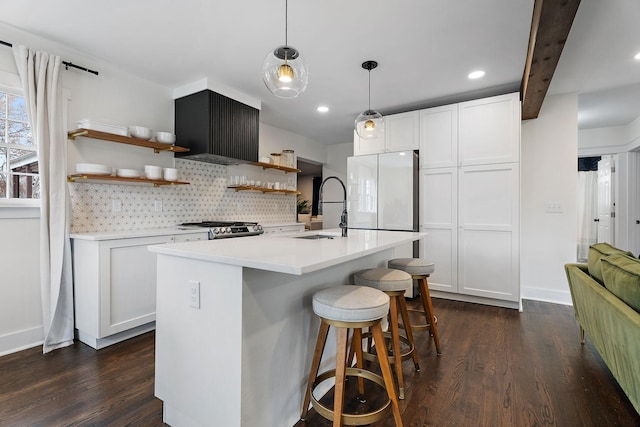 kitchen featuring an island with sink, sink, white fridge, and white cabinets