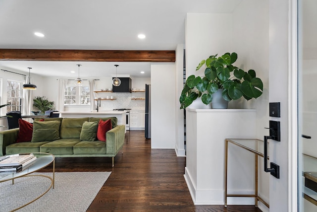 living room featuring sink, beam ceiling, and dark hardwood / wood-style floors