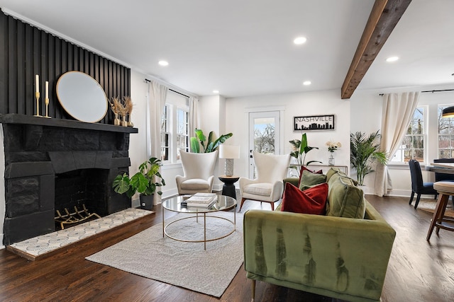 living room with beamed ceiling, a stone fireplace, and hardwood / wood-style floors