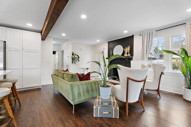 living room featuring beamed ceiling and dark wood-type flooring