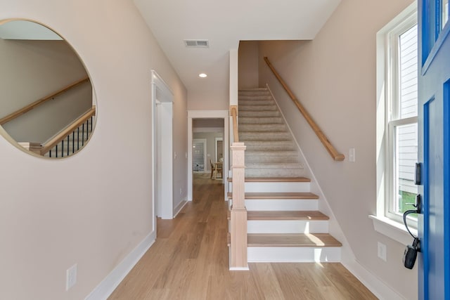 staircase with wood-type flooring and a healthy amount of sunlight