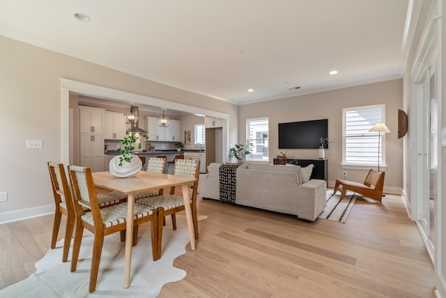 dining area with ornamental molding and light hardwood / wood-style floors