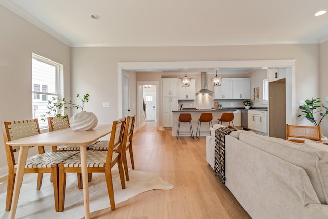 dining area with ornamental molding and light hardwood / wood-style flooring