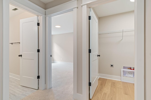 clothes washing area featuring electric dryer hookup and light hardwood / wood-style flooring