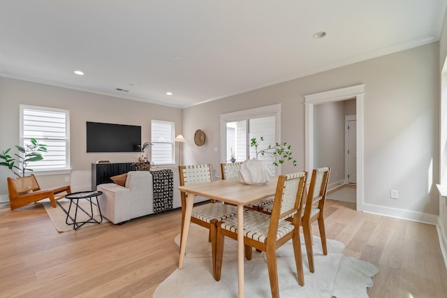 dining space with crown molding, light hardwood / wood-style flooring, and a wealth of natural light