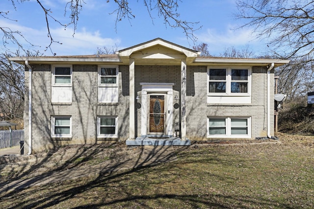 raised ranch featuring brick siding and fence