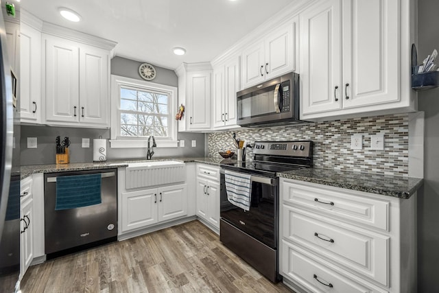 kitchen featuring white cabinetry, appliances with stainless steel finishes, sink, and dark stone counters