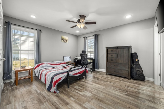 bedroom with ceiling fan, light hardwood / wood-style floors, and multiple windows