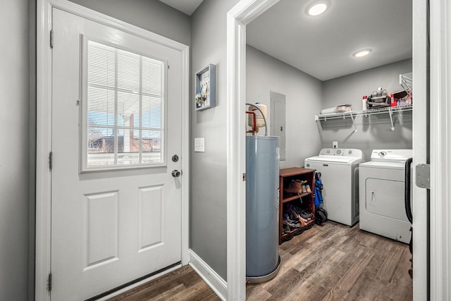 clothes washing area featuring water heater, dark wood-type flooring, electric panel, and washer and clothes dryer