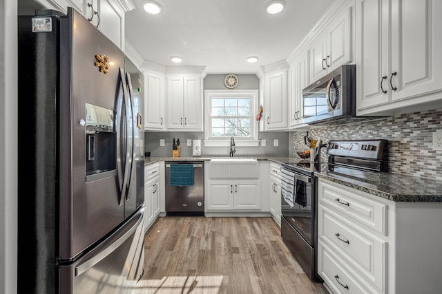 kitchen featuring white cabinetry, decorative backsplash, stainless steel appliances, and dark stone countertops