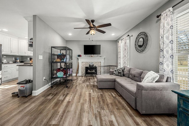 living room featuring ceiling fan, dark hardwood / wood-style floors, and a fireplace