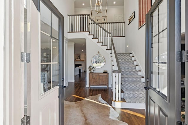 foyer entrance featuring dark wood-type flooring, ornamental molding, and a chandelier