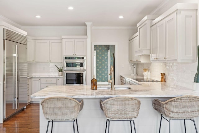 kitchen featuring white cabinetry, a kitchen bar, kitchen peninsula, stainless steel appliances, and crown molding