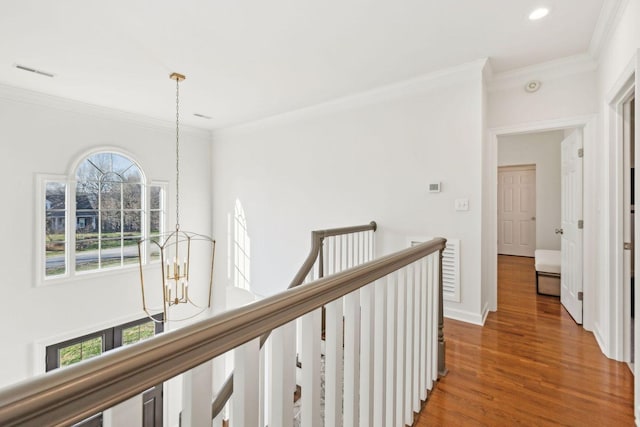 corridor with an inviting chandelier, crown molding, and wood-type flooring