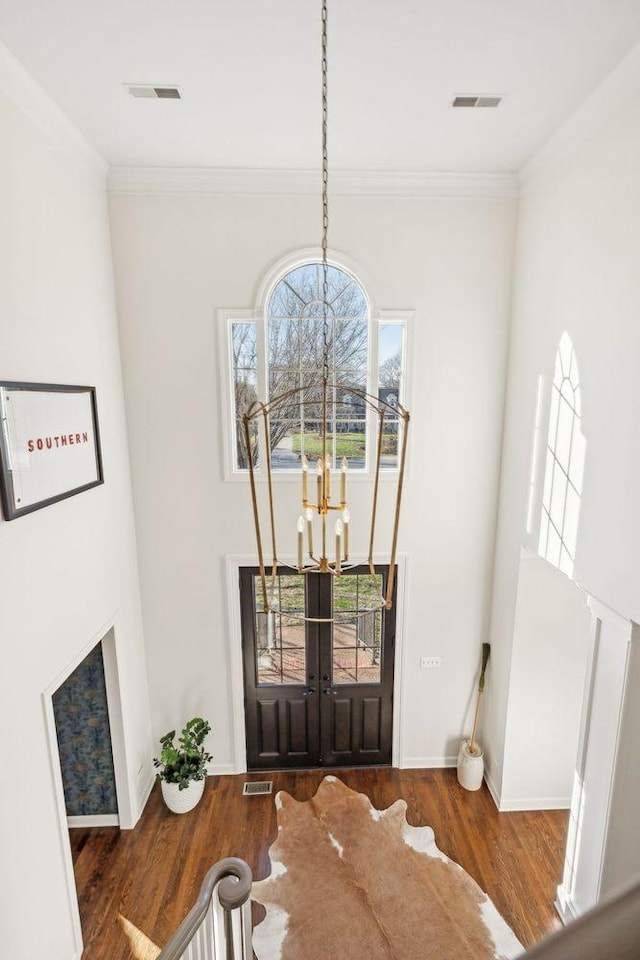 entryway with an inviting chandelier, ornamental molding, dark hardwood / wood-style flooring, and french doors