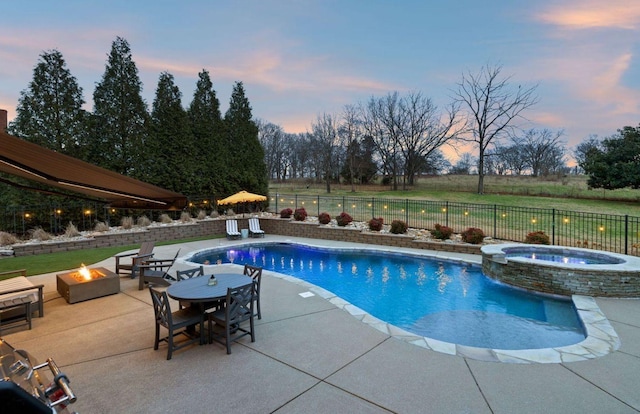 pool at dusk with a fire pit, a patio, and an in ground hot tub