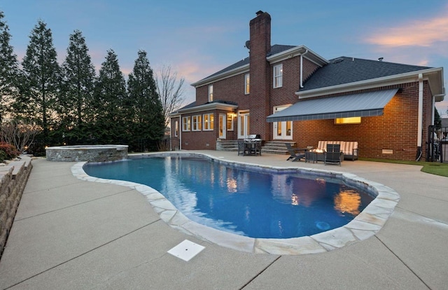 pool at dusk featuring an in ground hot tub, a grill, an outdoor fire pit, and a patio area