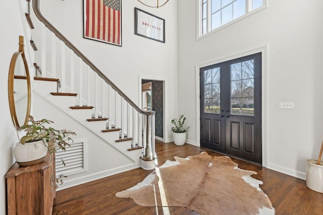 foyer with a towering ceiling, dark hardwood / wood-style flooring, and french doors