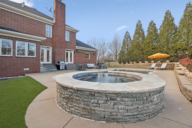 view of pool featuring french doors, an in ground hot tub, pool water feature, grilling area, and a patio area