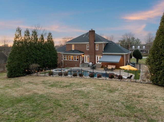 back house at dusk featuring a fenced in pool, a yard, and a patio area