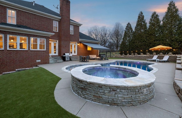 pool at dusk featuring an in ground hot tub, a grill, and a patio