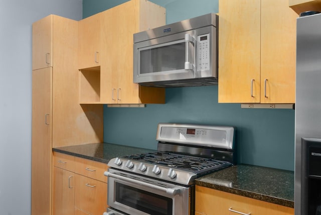 kitchen with appliances with stainless steel finishes and dark stone countertops