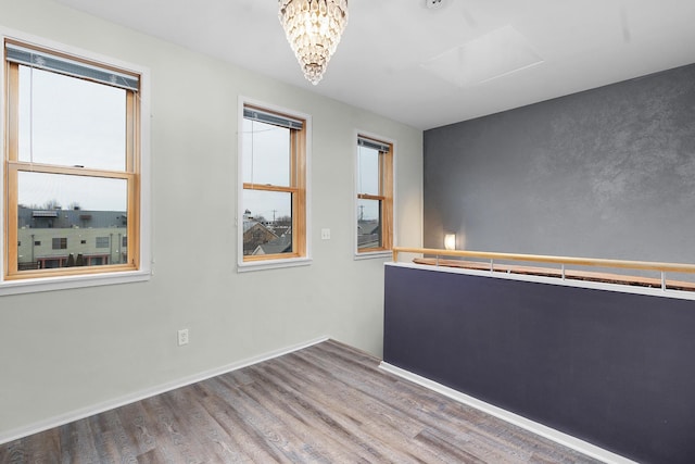 spare room featuring an inviting chandelier and wood-type flooring