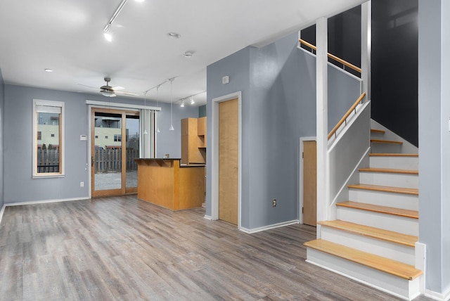 unfurnished living room with ceiling fan, track lighting, and hardwood / wood-style floors