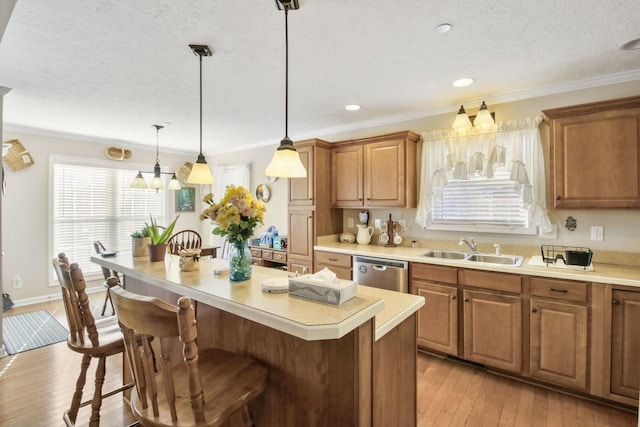 kitchen featuring a breakfast bar, sink, decorative light fixtures, a center island, and stainless steel dishwasher