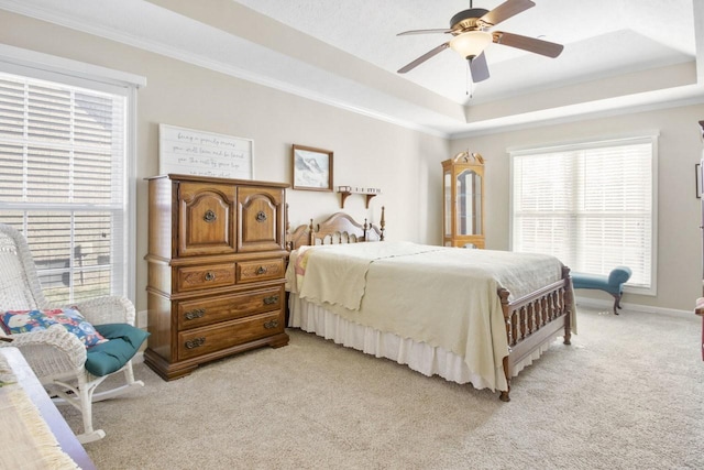 bedroom featuring a raised ceiling, ornamental molding, light carpet, and ceiling fan